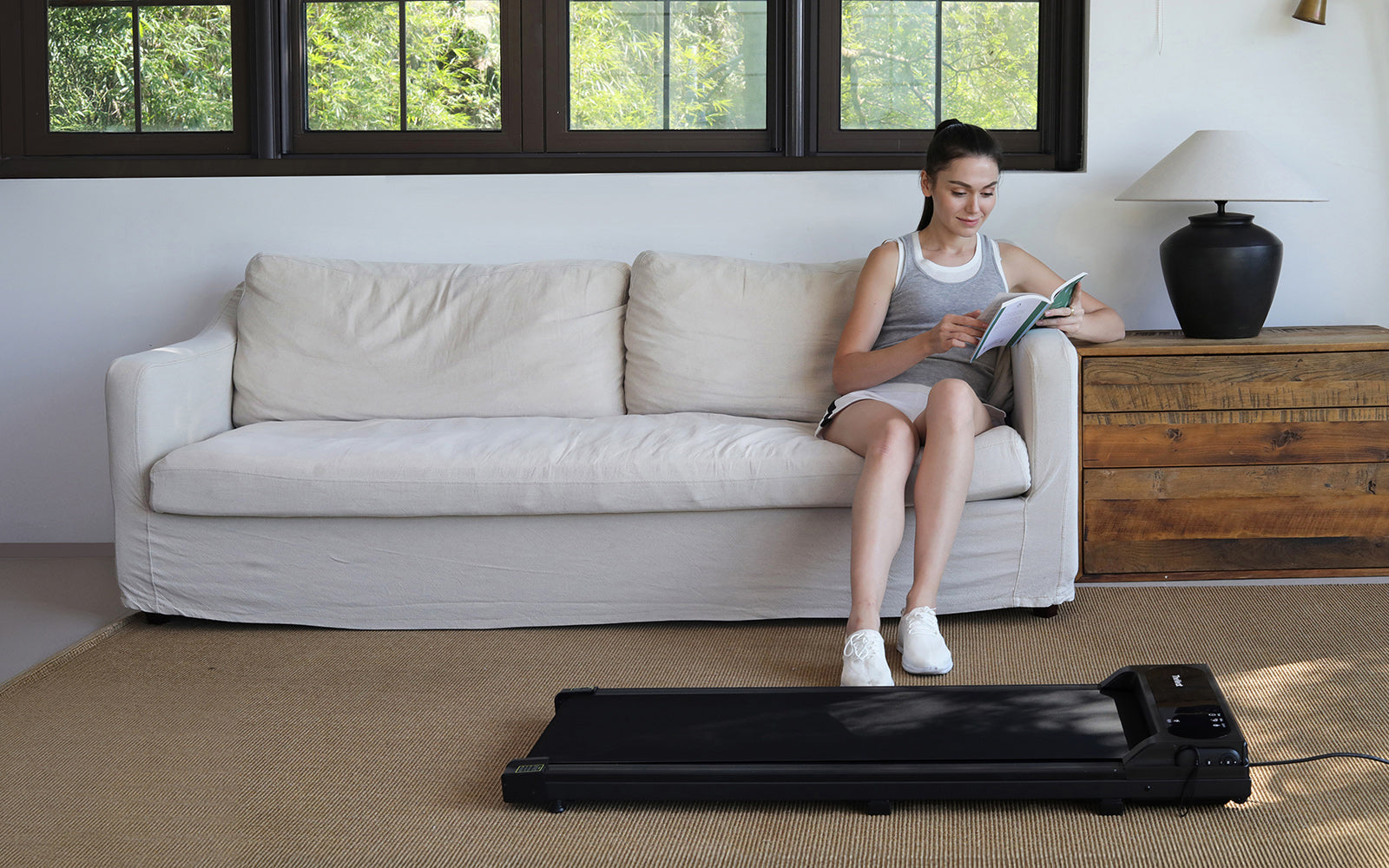 woman-reading-a-book-at-home-and-preparing-to-run-on-treadmill