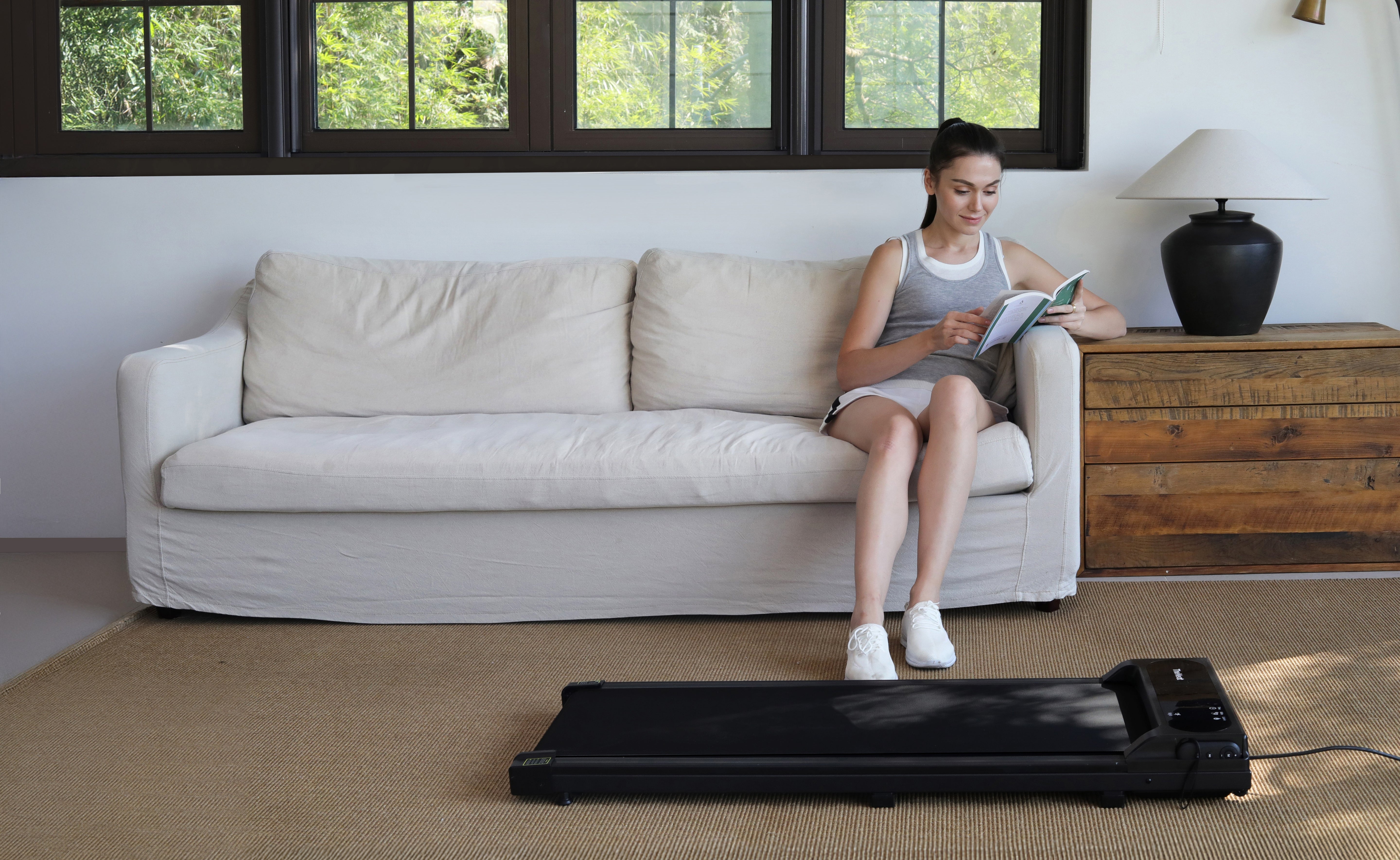 woman-reading-a-book-at-home-and-preparing-to-run-on-treadmill